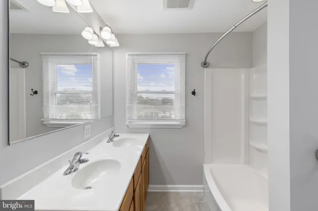 a bathroom with a tub a sink and a large mirror