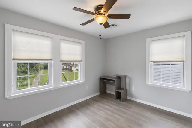 a view of an empty room with window and wooden floor