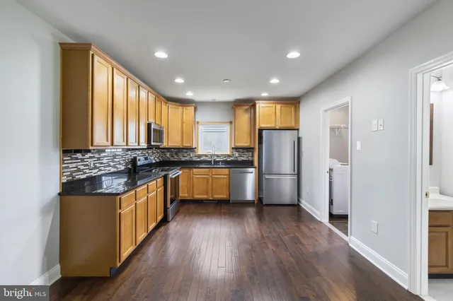 a kitchen with stainless steel appliances granite countertop a refrigerator a sink dishwasher a stove and white countertops with wooden floor