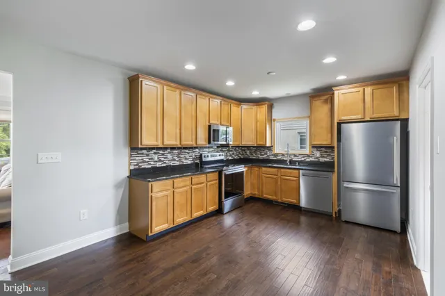 a kitchen with granite countertop stainless steel appliances a refrigerator cabinets and wooden floor