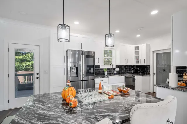 a outdoor kitchen with stainless steel appliances kitchen island granite countertop a refrigerator and wooden floor