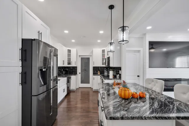 a kitchen with stainless steel appliances kitchen island granite countertop a refrigerator a stove and a sink with wooden floor