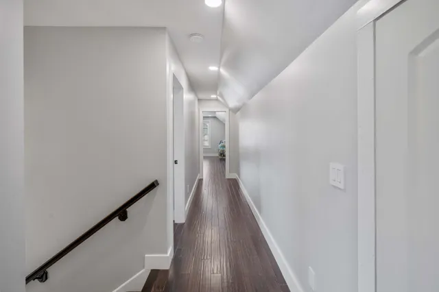 a view of a hallway with wooden floor and staircase