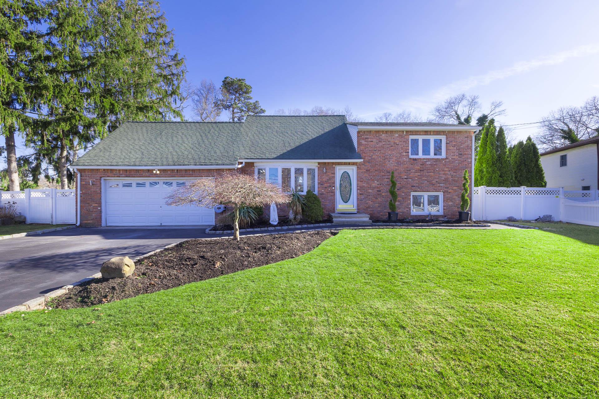84 Riverside Avenue Mastic Beach, NY 11951 - Photo 1 of 32 Tri-level home featuring brick siding, fence, concrete driveway, and a front yard