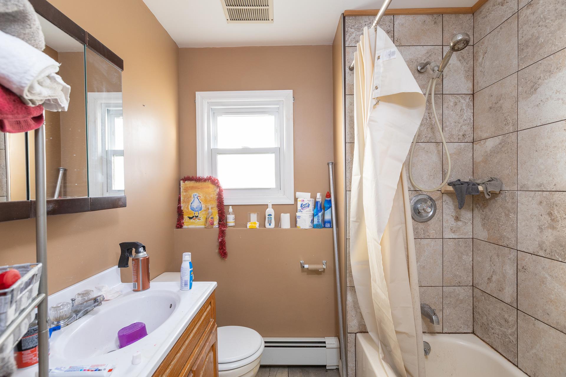 84 Riverside Avenue Mastic Beach, NY 11951 - Photo 20 of 32 Bathroom featuring shower / bath combo, visible vents, toilet, vanity, and a baseboard heating unit