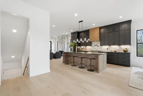a kitchen with stainless steel appliances kitchen island granite countertop a table chairs and a refrigerator