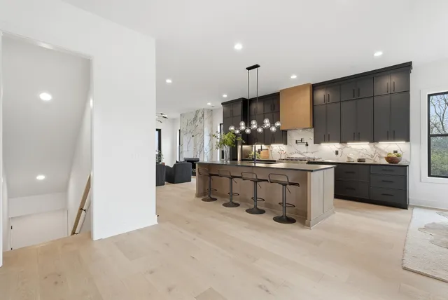 a kitchen with stainless steel appliances kitchen island granite countertop a table chairs and a refrigerator