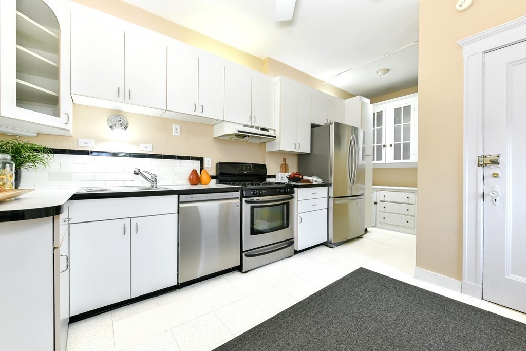 411 Washington Street, Unit 6 Brookline, MA 02446 - Photo 12 of 32 a kitchen with granite countertop white cabinets and stainless steel appliances