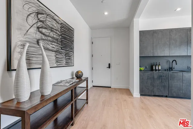 a view of an empty room with kitchen and a window