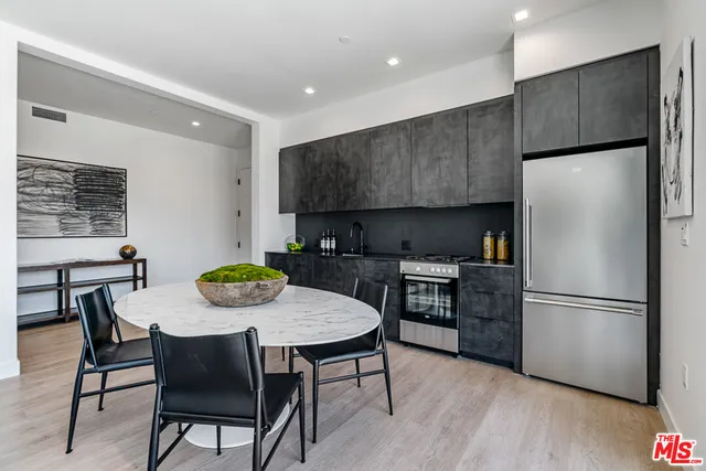 a kitchen with stainless steel appliances a dining table chairs refrigerator and microwave