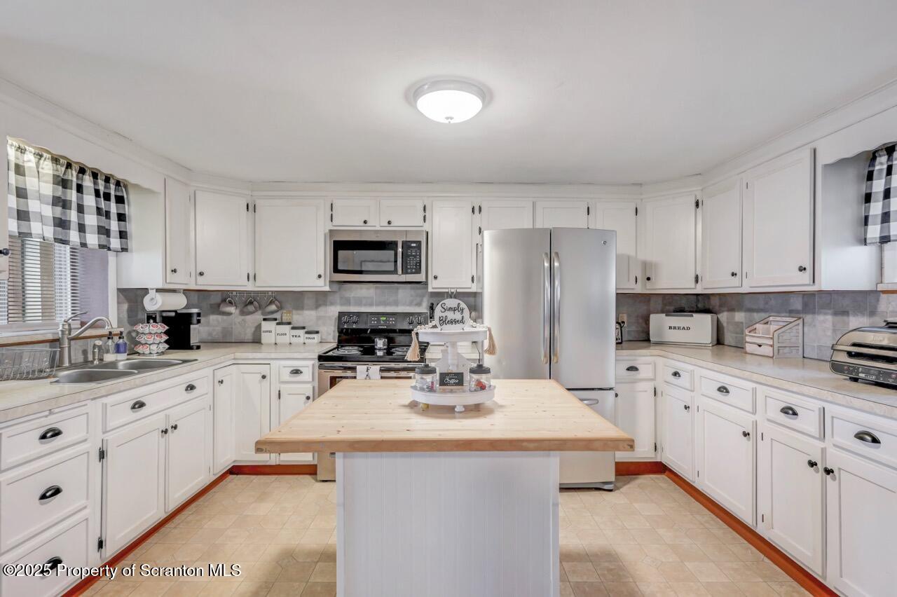 167 Handley Street Eynon, PA 18403 - Photo 13 of 48 a kitchen with stainless steel appliances a sink a stove a refrigerator cabinets and a window