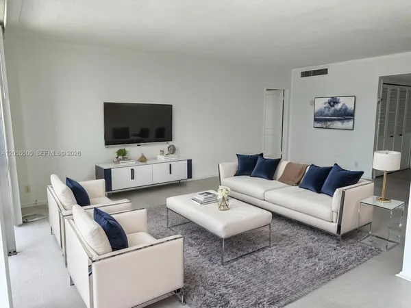 a living room with furniture a flat screen tv and a window