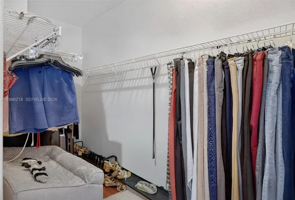 a view of walk in closet with clothes and shoes