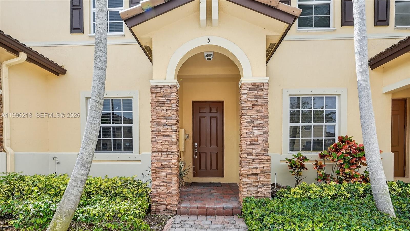 9041 Southwest 227th Street, Unit 5 Cutler Bay, FL 33190 - Photo 3 of 41 a front view of a house with a garden
