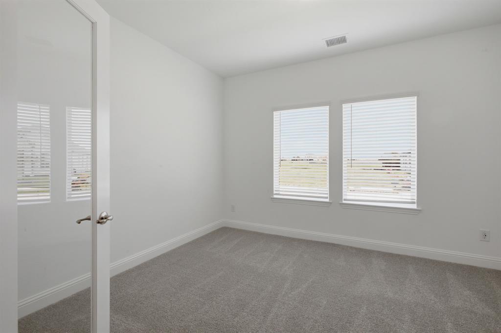 2911 Hanscom Street Forney, TX 75126 - Photo 7 of 40 Neutral-toned room featuring a glass-paneled door with brushed nickel hardware, two windows with horizontal blinds, light gray carpeting, and white baseboards