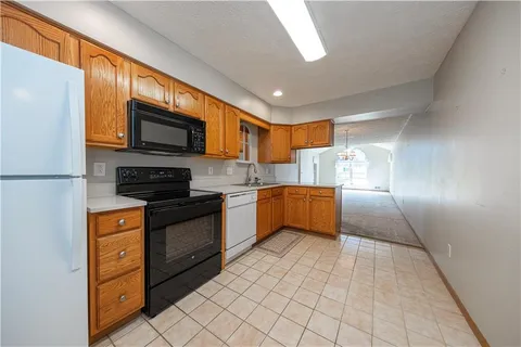 a kitchen with stainless steel appliances granite countertop a refrigerator a stove top oven a sink dishwasher and white cabinets with wooden floor