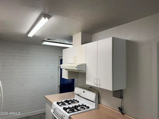 a kitchen with a sink and a stove with wooden floor