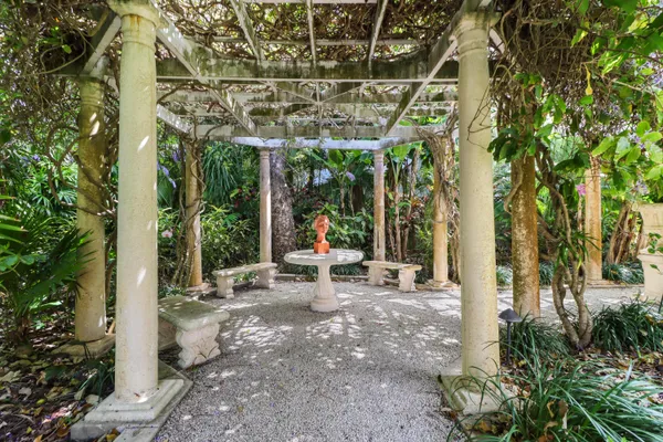 a view of a patio with table and chairs potted plants and large tree