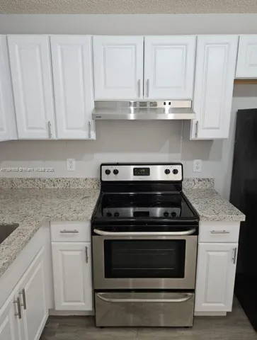 a kitchen with granite countertop white cabinets and appliances