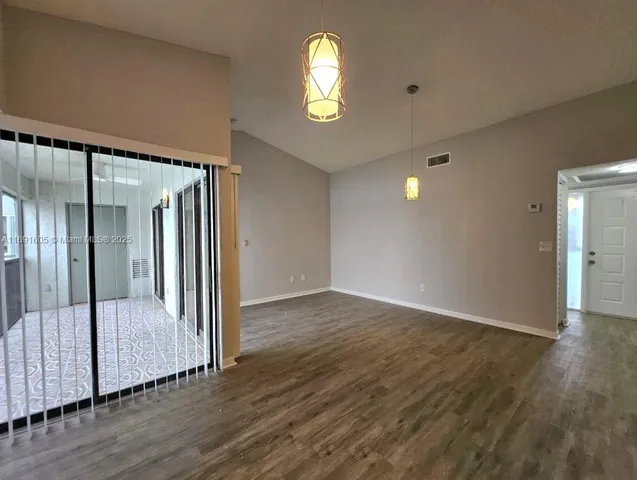 an empty room with wooden floor and a chandelier fan