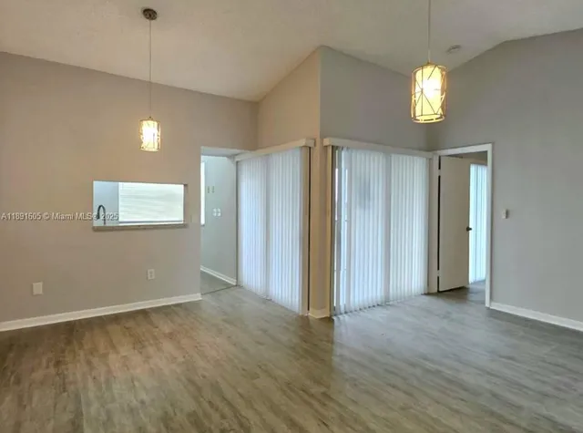 a view of an empty room with window and wooden floor