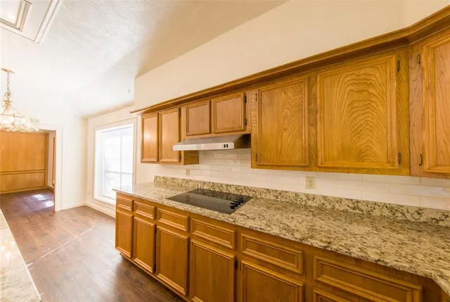 a kitchen with granite countertop wooden cabinets a sink and dishwasher