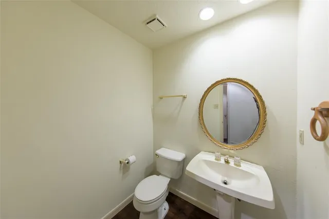 a bathroom with a toilet sink mirror and vanity