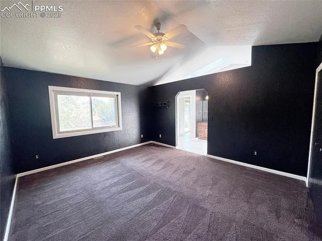 an empty room with closet and a chandelier fan