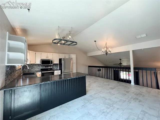 a kitchen with stainless steel appliances granite countertop a refrigerator a sink dishwasher a stove a refrigerator and a chandelier