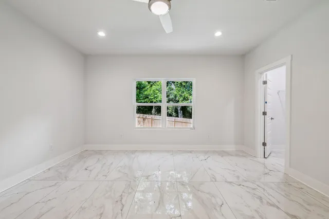 an empty room with wooden floor closet and windows