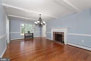a view of a livingroom with a fireplace a chandelier and wooden floor