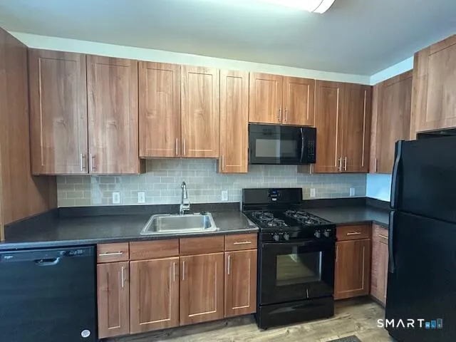 a kitchen with granite countertop a refrigerator stove and sink with granite countertops