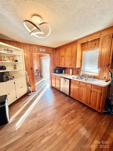 a large kitchen with stainless steel appliances wooden floors and a large window