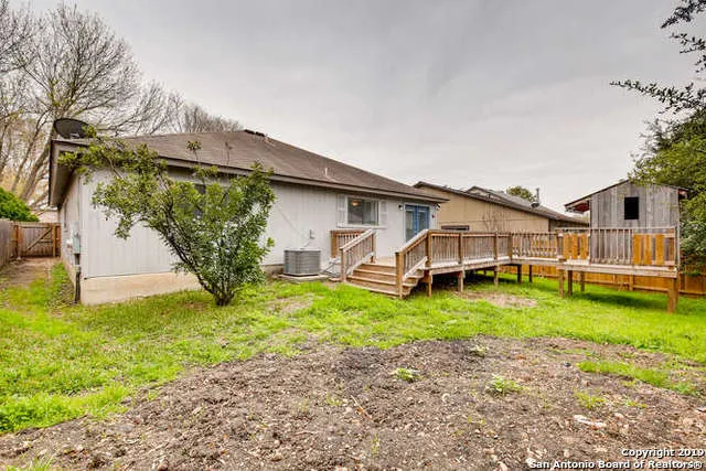 a white house that has a small yard and a big trees