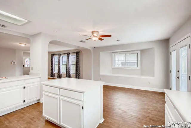 a living room with kitchen island a sink dishwasher and white cabinets with wooden floor