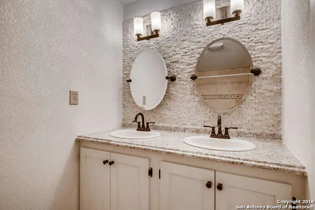 a bathroom with a granite countertop sink a mirror and vanity