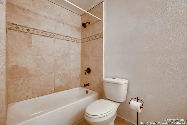 a white toilet sitting next to a bath tub and a shower