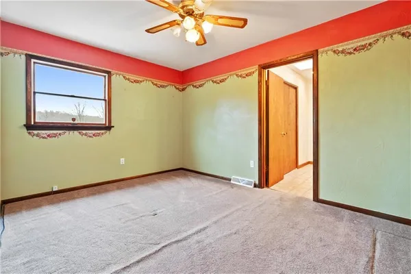 an empty room with windows and ceiling fan