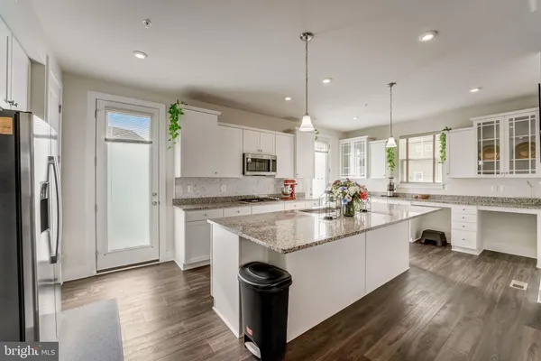 a large kitchen with kitchen island a sink appliances wooden floor and a window