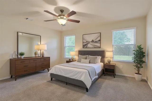a bedroom with a large bed and a chandelier fan