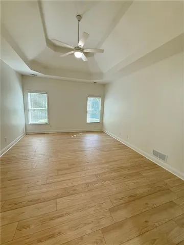 a view of an empty room with wooden floor and a ceiling fan