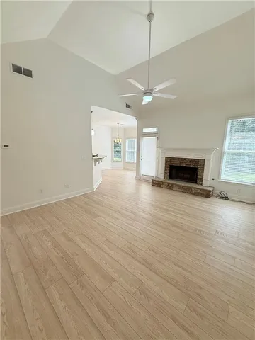 an empty room with wooden floor fireplace and windows