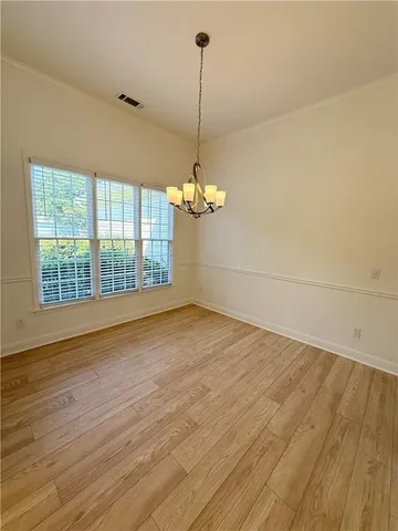 a view of a room with wooden floor chandelier and a window