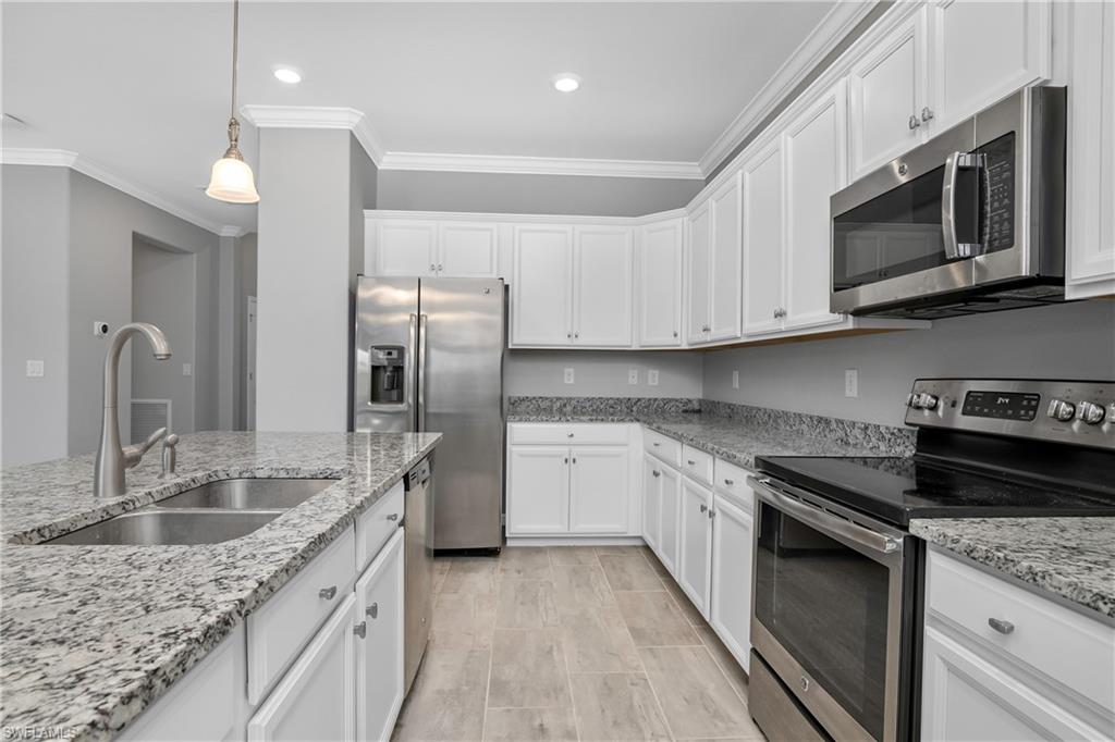 19952 Beverly Park Road Estero, FL 33928 - Photo 8 of 32 a kitchen with stainless steel appliances granite countertop a sink stove and microwave