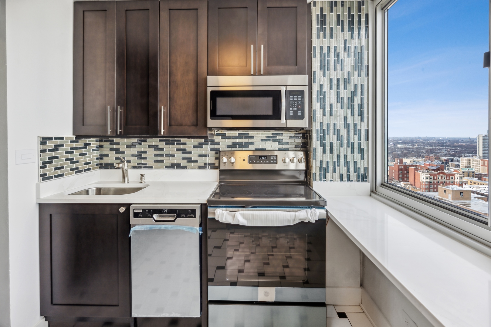 5601 North Sheridan Road, Unit 21E Chicago, IL 60660 - Photo 8 of 27 a kitchen with stainless steel appliances wooden cabinets and a stove top oven