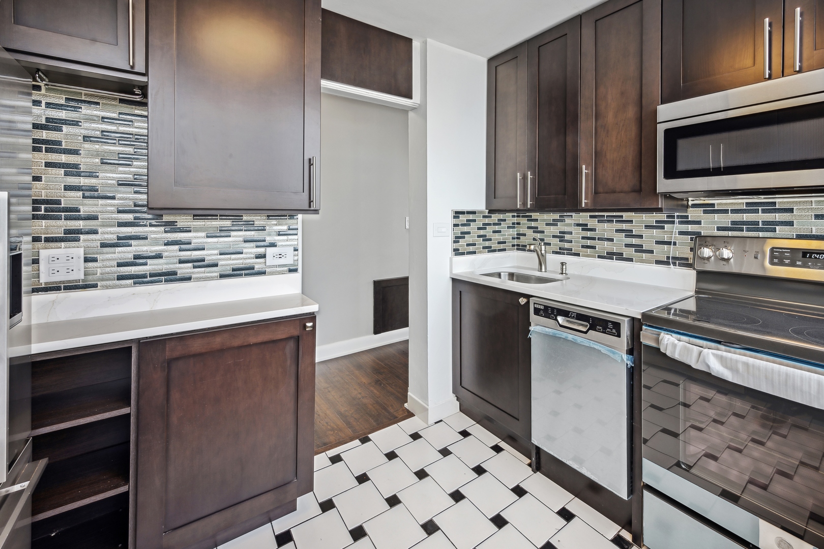 5601 North Sheridan Road, Unit 21E Chicago, IL 60660 - Photo 9 of 27 a kitchen with stainless steel appliances kitchen island granite countertop a sink stove and microwave