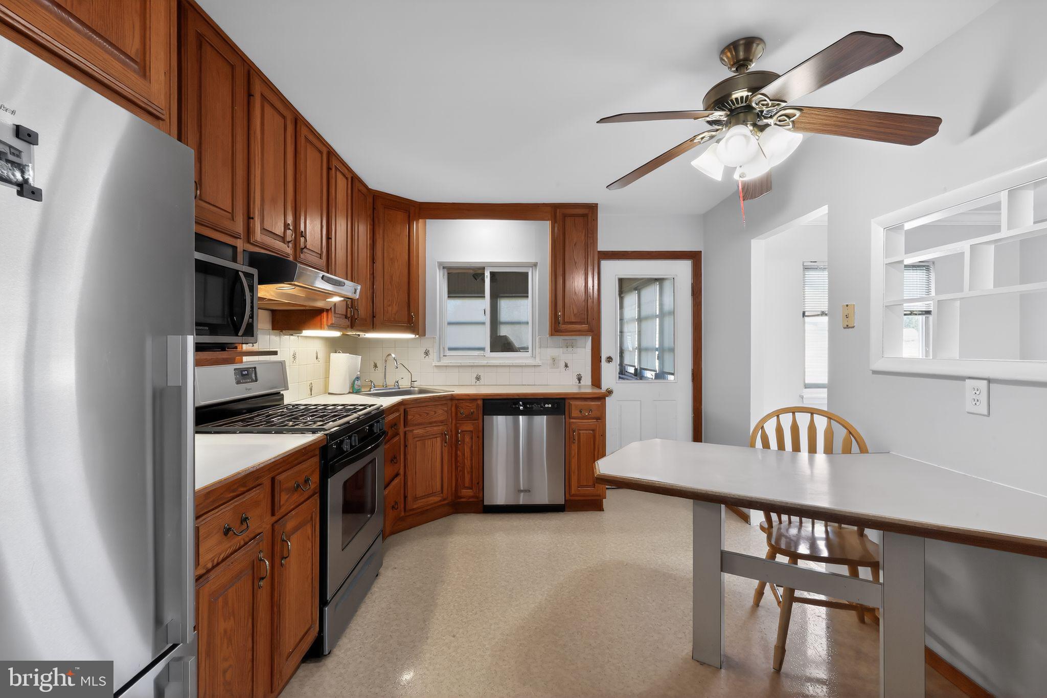 214 Bluefield Road Newark, DE 19713 - Photo 9 of 28 a kitchen with stainless steel appliances granite countertop a refrigerator a sink dishwasher a stove and a dining table with wooden floor