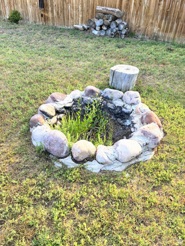 547 East 2000th Street North Vernal, UT 84078 - Photo 50 of 50 Backyard featuring a stone-lined fire pit, a wooden fence boundary, and a log stack