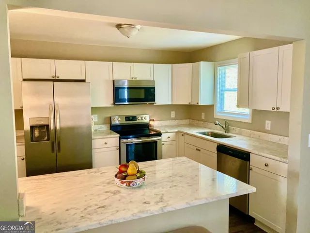 a kitchen with stainless steel appliances kitchen island granite countertop a refrigerator stove and sink