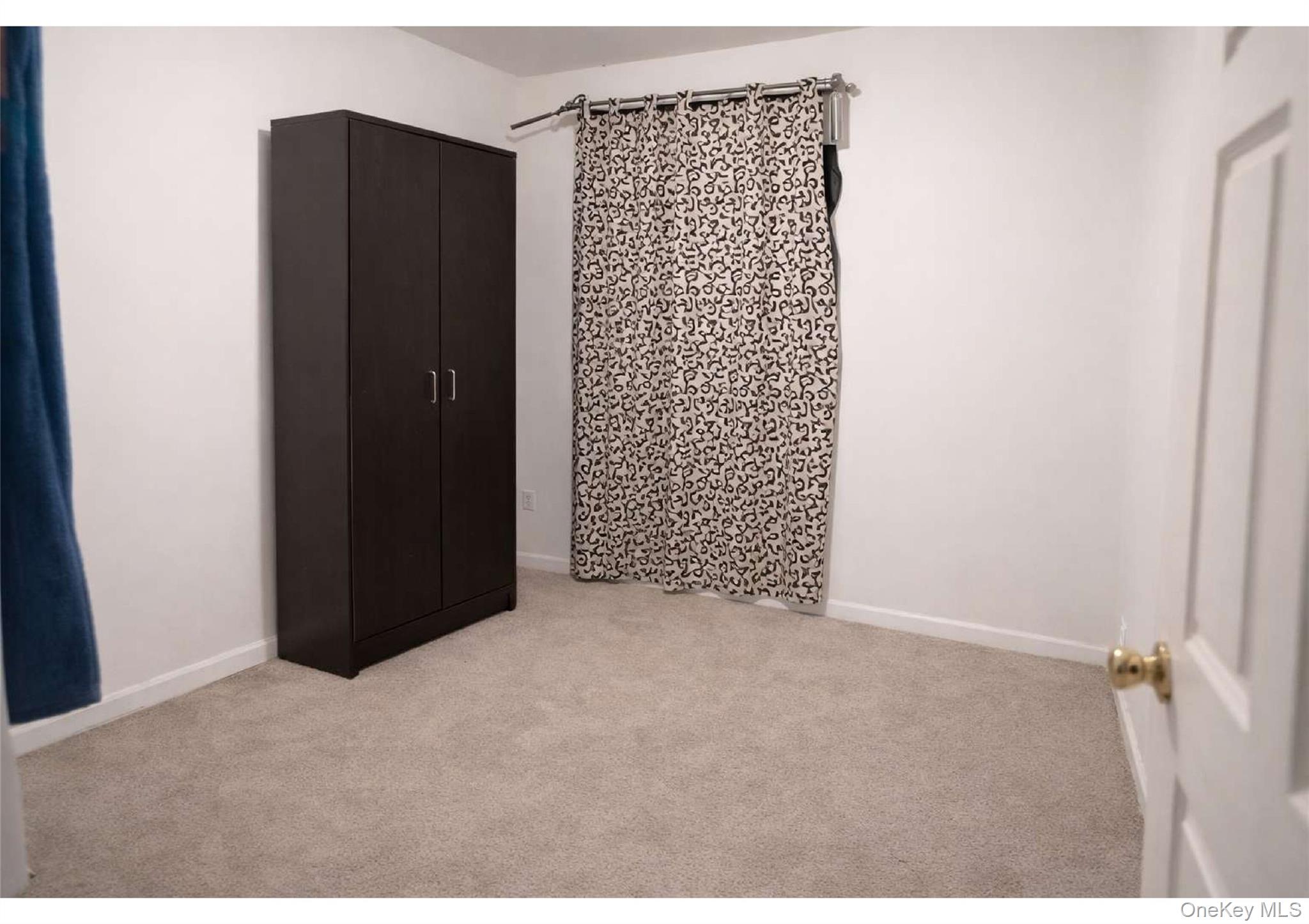 85-40 79th Street Queens, NY 11421 - Photo 12 of 19 Unfurnished bedroom featuring light carpet and baseboards